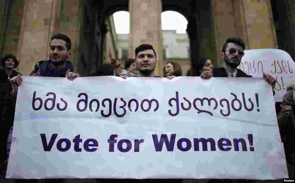 Men hold a banner during a protest demanding stronger women's political representation and engagement in parliament in front of the Parliament building on International Women's Day in Tbilisi, March 8, 2015.