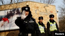 在加拿大驻北京大使馆外的一名中国警察向摄影记者打出禁止的手势。(2018年12月20日)