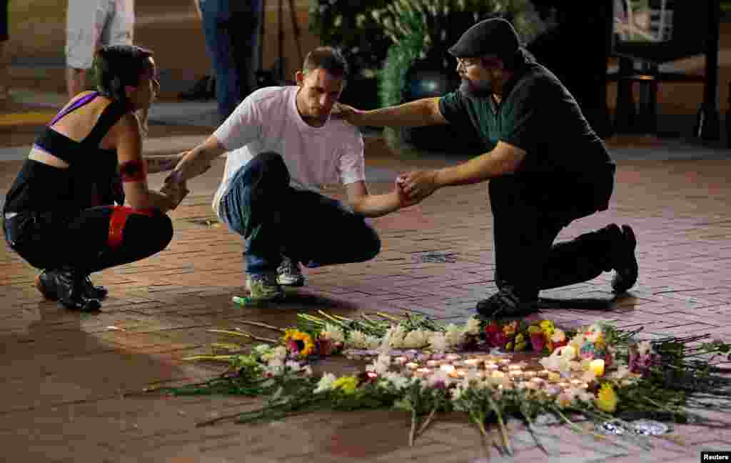 Two people stop to comfort Joseph Culver (C) of Charlottesville as he kneels at a late night vigil to pay his respect for a friend injured in a car attack on counter protesters after the "Unite the Right" rally organized by white nationalists in Charlottesville, Aug. 12, 2017.