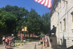 资料照片:游人与哈佛大学的约翰·哈佛铜像合影。