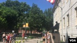 资料照片:游人与哈佛大学的约翰·哈佛铜像合影。