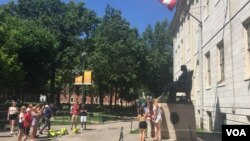 资料照片:游人与哈佛大学的约翰·哈佛铜像合影。