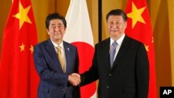 资料照:中国国家主席习近平和大阪与日本首相安倍晋三握手。(2019年6月27日)