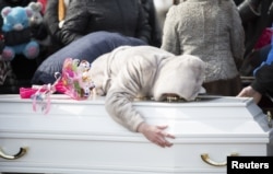 在为一名克麦罗沃商城火灾受害者举行的葬礼期间,一位女士在墓地抚棺痛苦。(2018年3月28日)