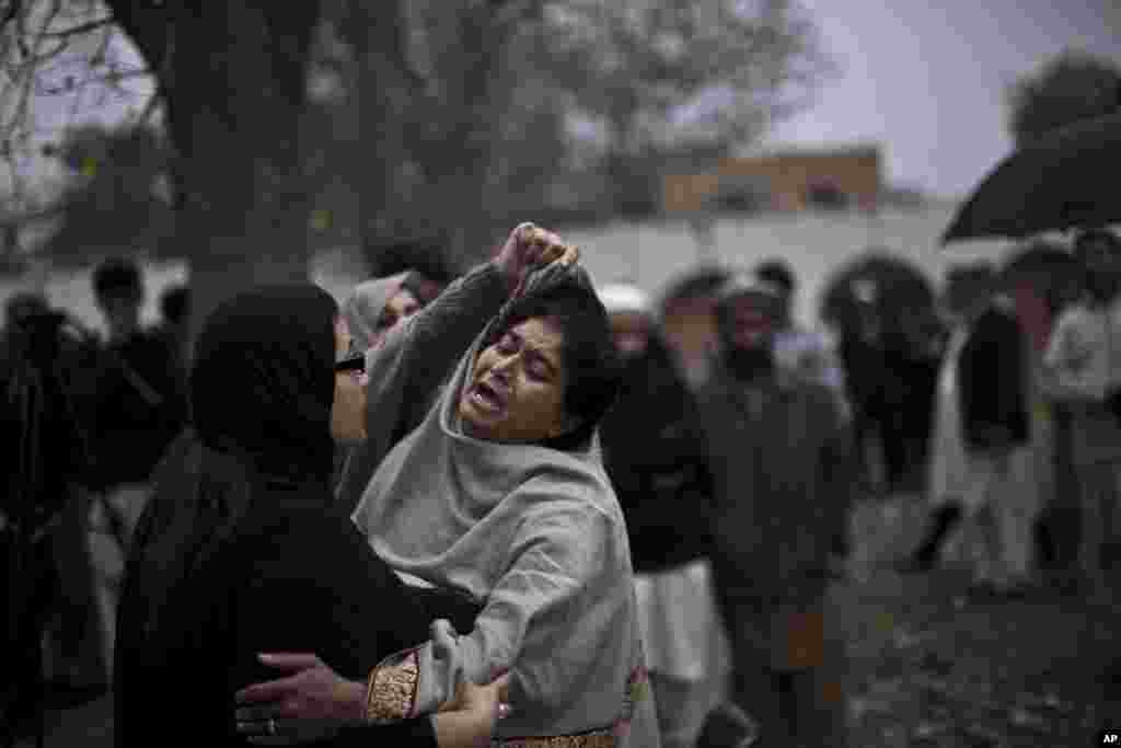 A woman comforts a woman grieving outside a hospital's morgue, where the bodies of victims of a twin suicide bombing were taken, Islamabad, March 3, 2014.
