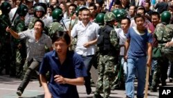 资料照:手持棍棒的汉族人冲破武警人墙,试图攻击维族地段。(2009年7月7日)