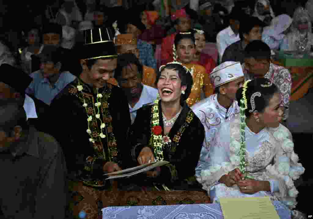 A bride and groom react to their marriage documents during a mass wedding held in celebration of the New Year in Jakarta, Indonesia, Sunday, Dec. 31, 2017.