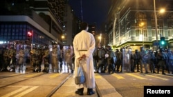 在香港坚尼地城,一名宗教人士站在防暴警察前。(2019年8月4日)