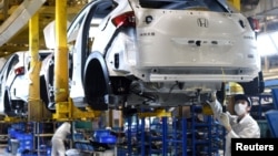 资料照:中国湖北武汉的东风集团本田汽车公司的工人在生产线上工作。(2020年3月16日)