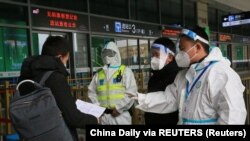 12月23日,警察和防疫人员在西安火车站检查旅客的文件。