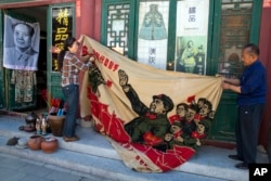 北京旧货市场上的1969年的文革横幅画布,上面有戴红卫兵袖章的毛泽东、江青和红卫兵。横幅上写着“大海航行靠舵手” 和“毛主席检阅文化革命大军”(2016年5月16日)