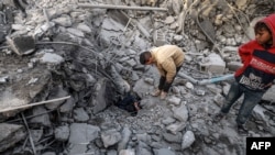 以色列轰炸加沙南部拉法后,巴勒斯坦人在一座清真寺和建筑的废墟上。(2024年1月24日)