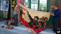 北京旧货市场上的1969年的文革横幅画布,上面有戴红卫兵袖章的毛泽东、其他文革领导人和红卫兵。横幅上写着“大海航行靠舵手” 和“毛主席检阅文化革命大军”(2016年5月16日)