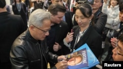 英伟达首席执行官黄仁勋在台湾为台北的粉丝们在杂志封面上签名。(2025年1月17日)