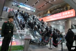 2025年1月18日,北京西站内站岗的武警士兵和准备乘坐火车回家过春节的返乡大军。