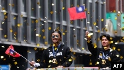 资料照:2024年11月26日,在台北,台湾棒球队队长陈杰宪(右)和球员林家正在庆祝球队赢得2024WBSC十二强棒球锦标赛冠军的游行中向人群挥手致意。(法新社)