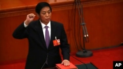 新当选的中国人大委员长栗战书2018年3月17日在全国人大全体会议上手按宪法,宣誓就职。