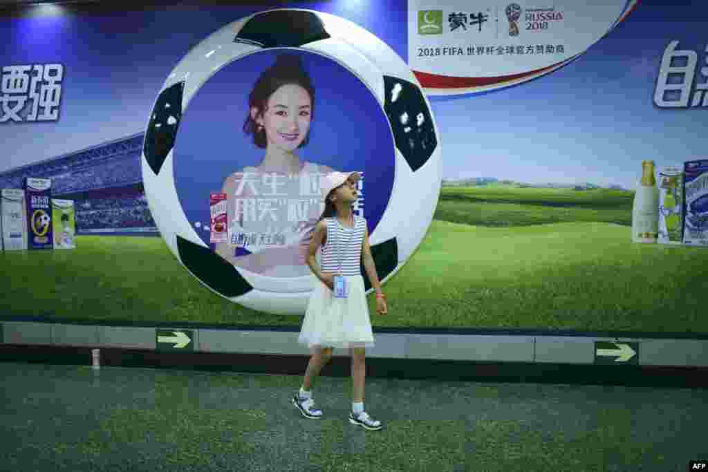 2018年6月1日,在北京的一个地铁站里,一位女士走过2018年世界杯足球赛赞助商——中国乳品公司蒙牛的广告。 中国队没有资格参加世界杯,但有数千名中国球迷将飞往俄罗斯,中国赞助商也将在全球电视屏幕上大展宏图。