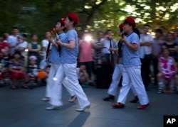 中国妇女在北京一座商城外的广场上随着革命歌曲跳舞,她们手中拿着玩具枪道具。(2014年1月29日)