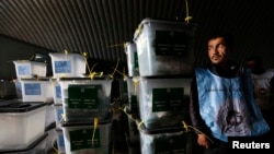 An Afghan election worker stands next to ballot boxes at a counting centre in Kabul, April 6, 2014.