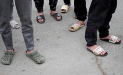 塞尔维亚北部城镇兹雷尼亚宁附近一家中国汽车轮胎工厂建筑工地工作的越南工人光着脚站在工房前。(2021年11月18日)