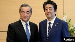 中国外长王毅在东京与日本首相安倍晋三握手。(2019年11月25日)