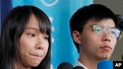 前“香港众志”的秘书长黄之锋及成员周庭(左)在一家地区法院前对媒体讲话。(2019年8月30日)