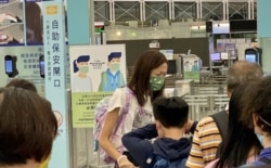 有香港家长带同年幼子女移民,在香港国际机场离境时与亲友依依惜别。(美国之音 / 汤惠芸)