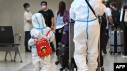 2021年11月29日,国际旅客带着个人防护设备抵达澳大利亚墨尔本机场。澳大利亚已经发现一例新冠病毒变异毒株奥密克戎。(法新社)