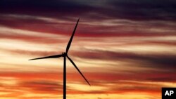 2023年11月29日,美国总统拜登访问全球最大的风塔制造商 CS Wind 之前,在科罗拉多州普韦布洛拍摄的太阳升起和风车的照片。(美联社照片)