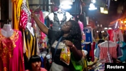 资料照:一名非洲妇女在中国广州的一个服装市场购物。(2014年10月25日)