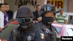 FILE - Mexican federal police officers are seen standing guard during a raid.
