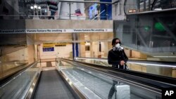 一名戴口罩的妇女在米兰中央火车站的电梯上。(2020年3月8日)