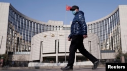 一名戴着口罩的男子走过北京的中国人民银行总部。(2020年2月3日)