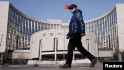 一名戴着口罩的男子走过北京的中国人民银行总部。(2020年2月3日)