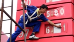 2009年7月29日: 工人在湖北省宜昌市加油站调整属于国营企业的中石化燃油价格标牌