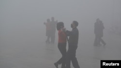 2017年1月3日,中国安徽阜阳市的广场上,戴口罩的人在严重雾霾中跳舞,苦中作乐。