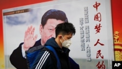 北京街道上,戴口罩的行人走过带有中国领导人习近平像的海报,海报上有标语“中国梦人民的梦”(2017年10月26日)