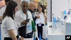 资料照片: 2023年11月4日广州进出口商品交易会上,参展商在推广保健设备的展位上接待外国参观者。