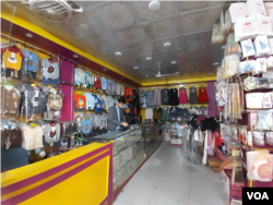 11月24日巴基斯坦白沙瓦卡尔卡诺市场的一家店铺里,一名商贩正在忙着整理从中国进口的成人服装和童装 (美国之音/沙基尔)