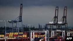 资料照片：2023年6月7日，在加利福尼亚州洛杉矶的洛杉矶港，卡车等待装载货物集装箱。