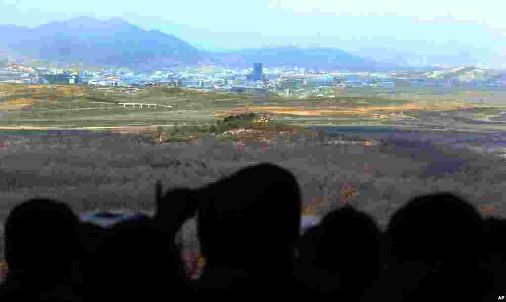 参观人士2013年4月9日在韩国坡州板门店村边境非军事区附近的多拉观测站用望远镜观看朝鲜开城的联合工业区。