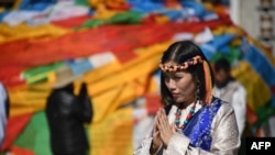 中国西藏自治区首府拉萨的大昭寺外面,一名穿着藏族传统服装的中国游客正在合什拍照(2016年9月10日)。