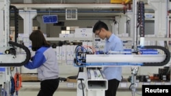 工人们在东莞一家工厂测试工业机器人。(2019年3月1日)