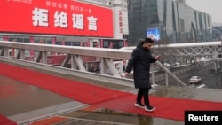 一名男子走过北京一家墙上挂有“拒绝谣言”标语的商场。(2020年2月6日)