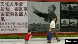 资料照:广东省汕头市举办文革展览,参观者走过的一幅毛泽东在文革期间的画像。(2007年4月25日)