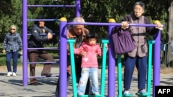 资料照:北京天坛公园里的老年人和他们的独生子女的孙辈在锻炼身体。(2011年10月25日)