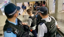 社民连4名成员十一游行途经行人天桥,数十名军装警员沿途包围戒备 (美国之音/汤惠芸)