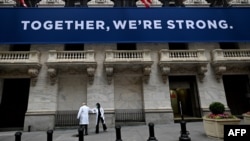 纽约证券交易所开市前,医护人员抵达时用手肘相互致意。在关闭了两个月之后,纽约证券交易所对交易员重新开放(2020年5月26日)。