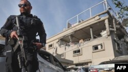 An Israeli policeman stands guard in front of a damaged building following a rocket attack from southern Lebanon that targeted the central Israeli-Arab city of Tira, on November 2, 2024, amid the ongoing war between Israel and Hezbollah. (Photo by JACK GUEZ / AFP) နိုဝင်ဘာ ၂ ရက်က လက်ဘနွန်တောင်ပိုင်းက ပစ်လွှတ်လိုက်တဲ့ ဒုံးကျည်တွေ ကျရောက်ခဲ့တဲ့ အစ္စရေး အလယ်ပိုင်း တီရာမြို့က ပျက်စီးသွားတဲ့ အဆောက်အအုံ
